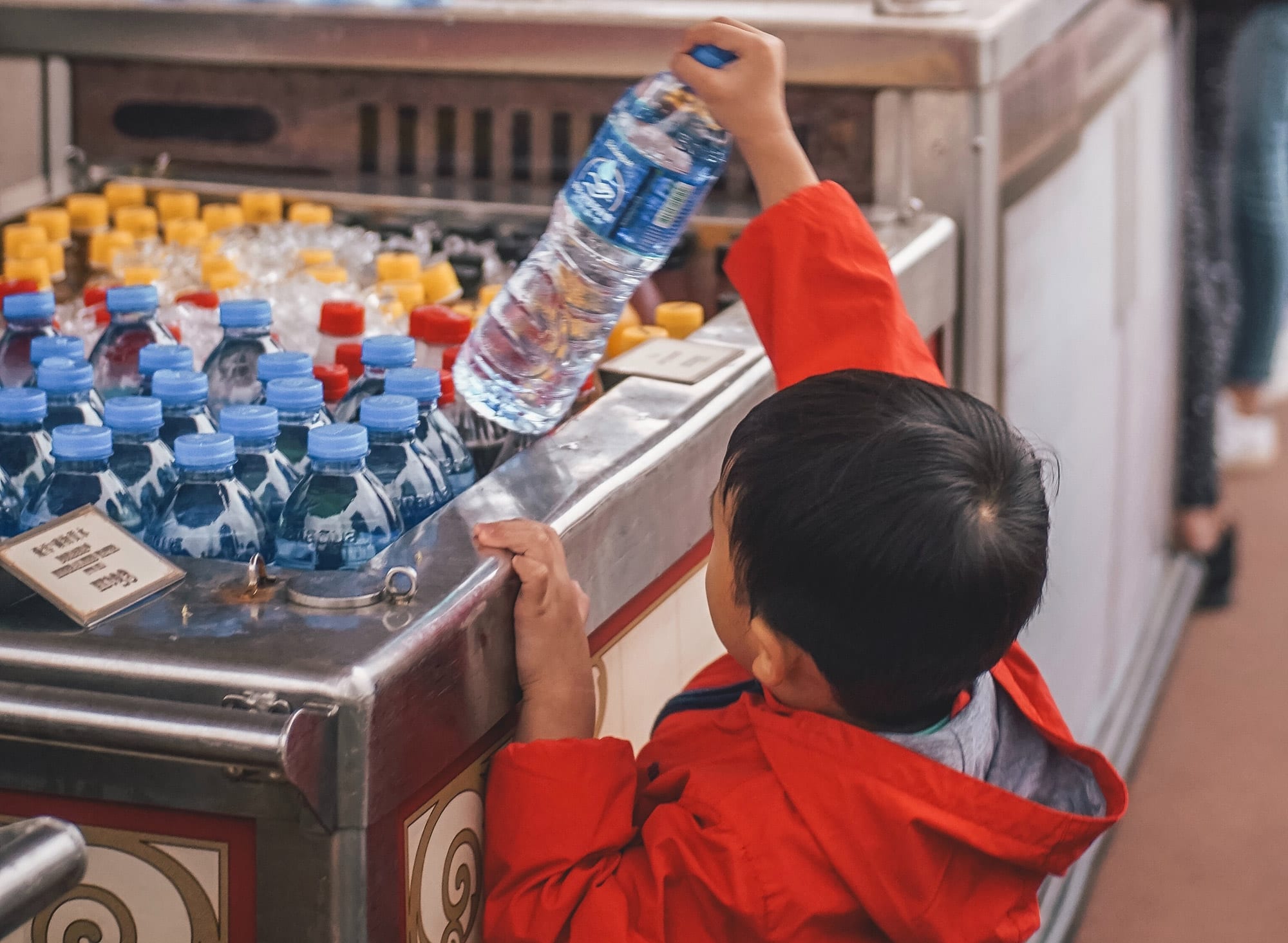 Young boy pickup a bottle of water. REVOLVE