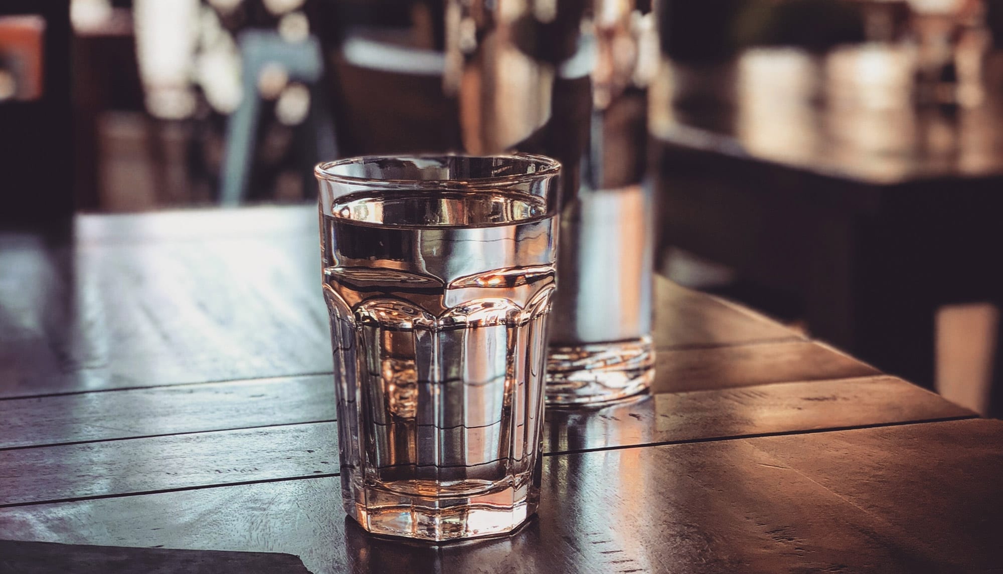 Glass of water on the wood table, REVOLVE