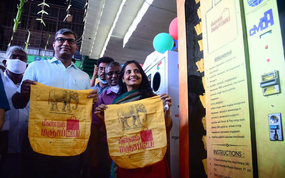 Six people Chennai Corporation next to reusable bags vending machines in Chennai, India. Example of circular economy.