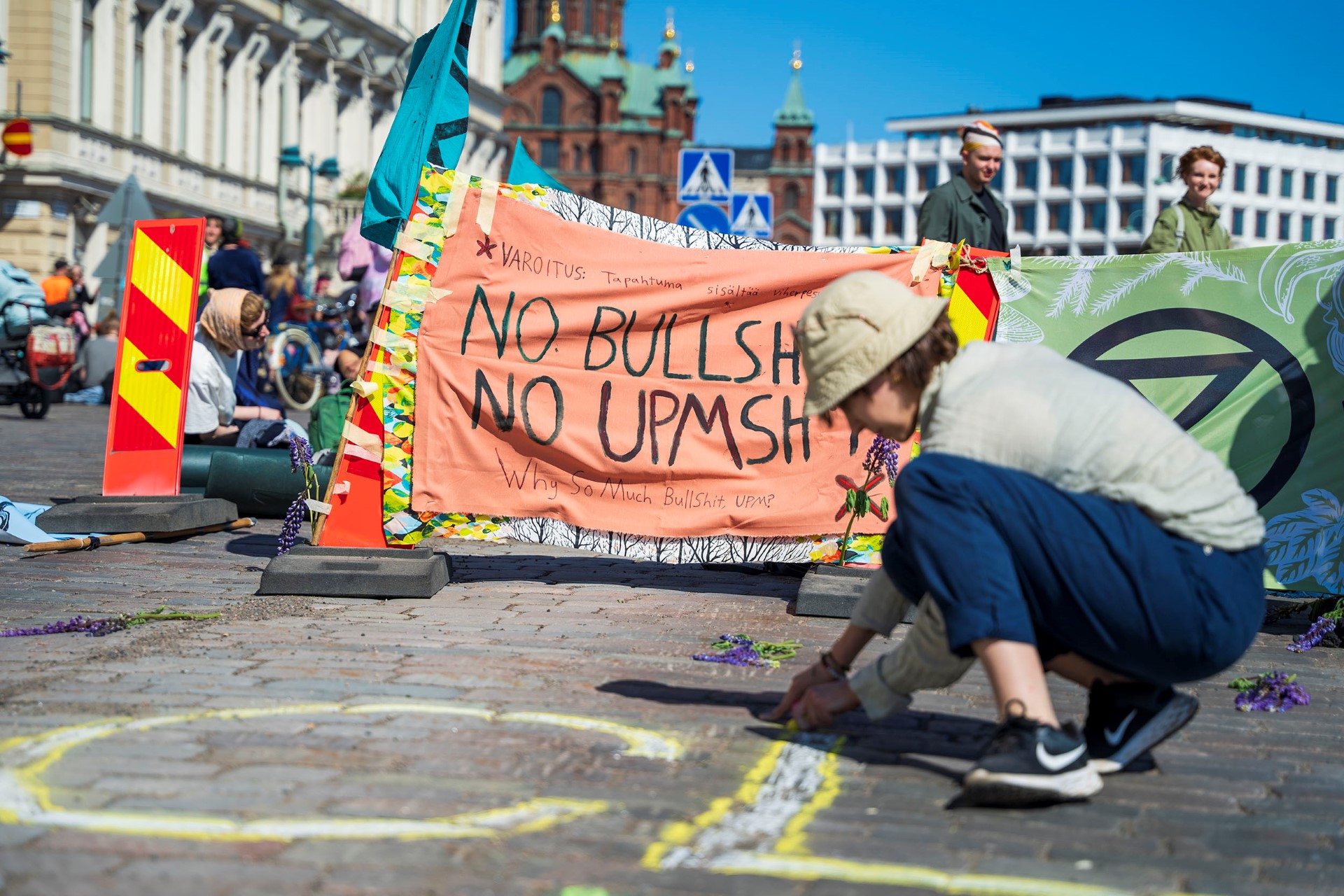 Another photo of a group of climate protestors advocating for the preservation of the forest ecosystem.  A man in front of a banner saying "No bullsh...; No UPM-sh...".