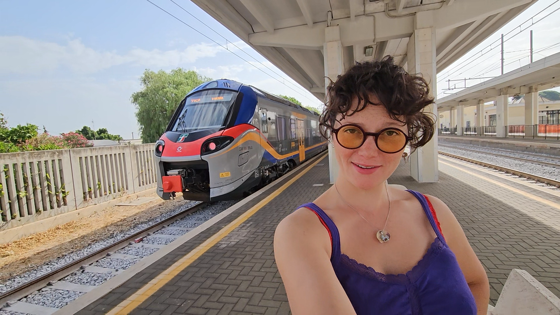 Clara Francken at a train station, with an Italian train behind her.