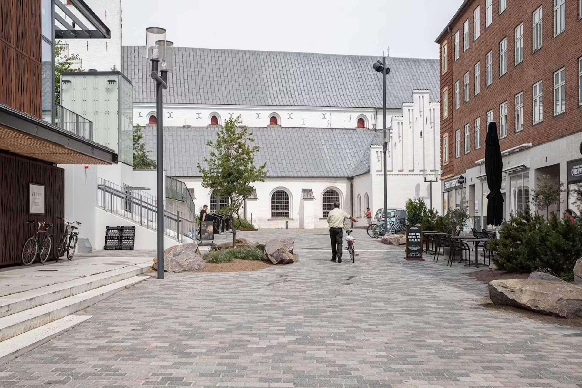 A cyclist walking by the cathedral in Aalborg.