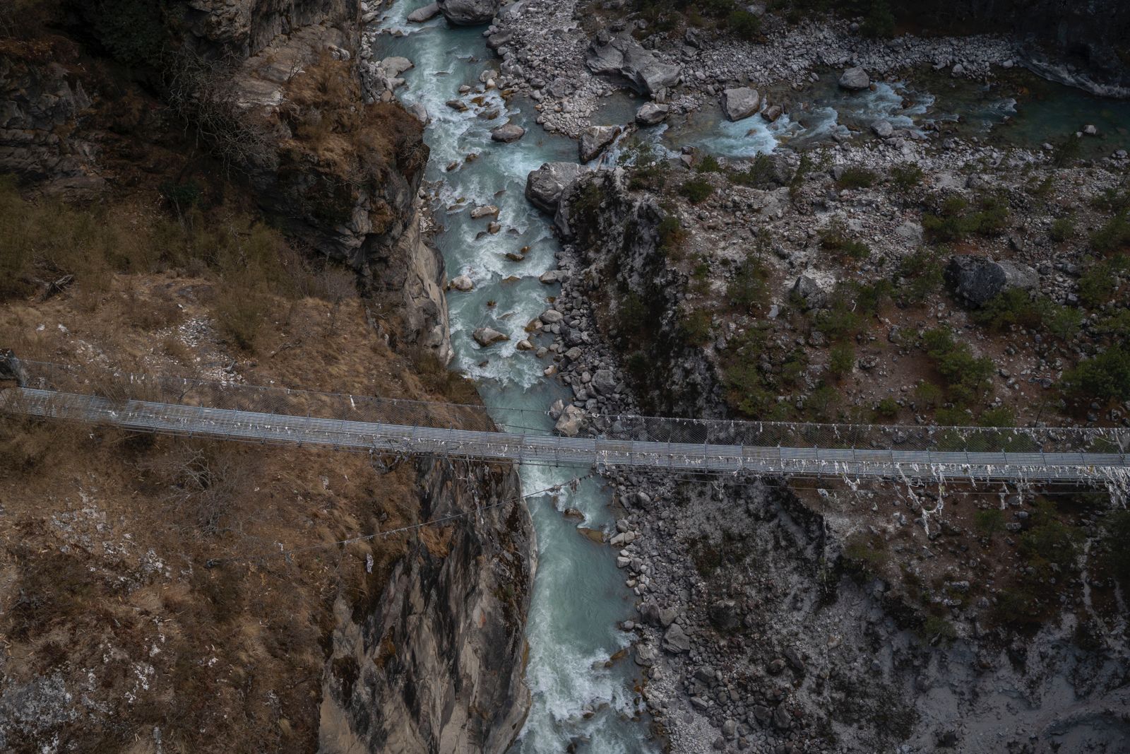 A photo of a suspension bridge over the Himalayas waters - the Dudh Koshi River.